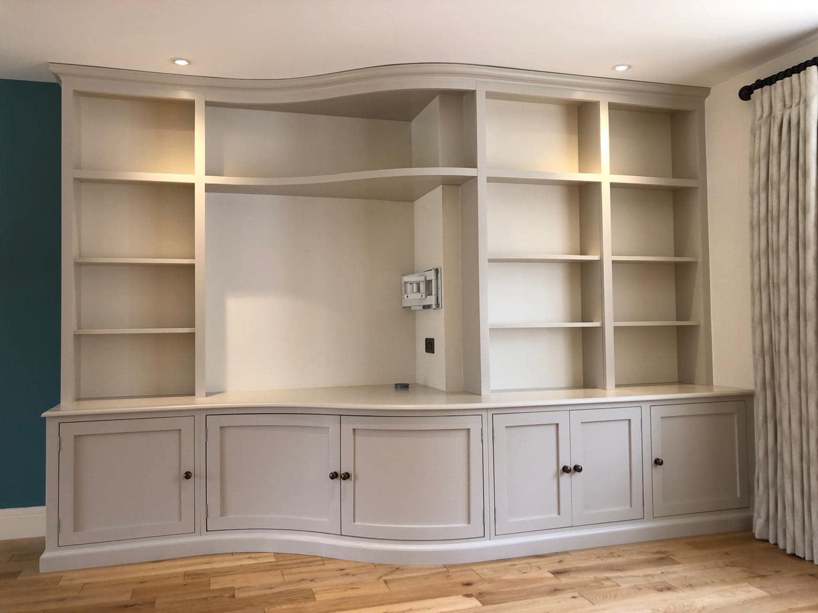 A curved book case and TV unit in a well lit room