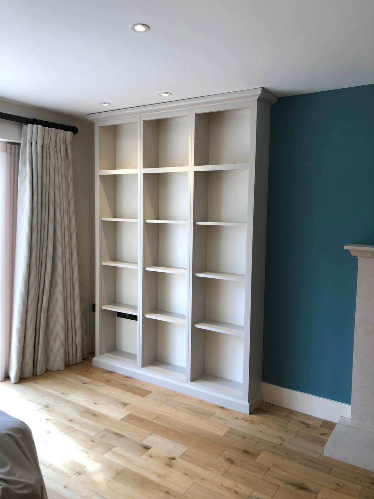 a tall light grey bookcase on a wooden floor