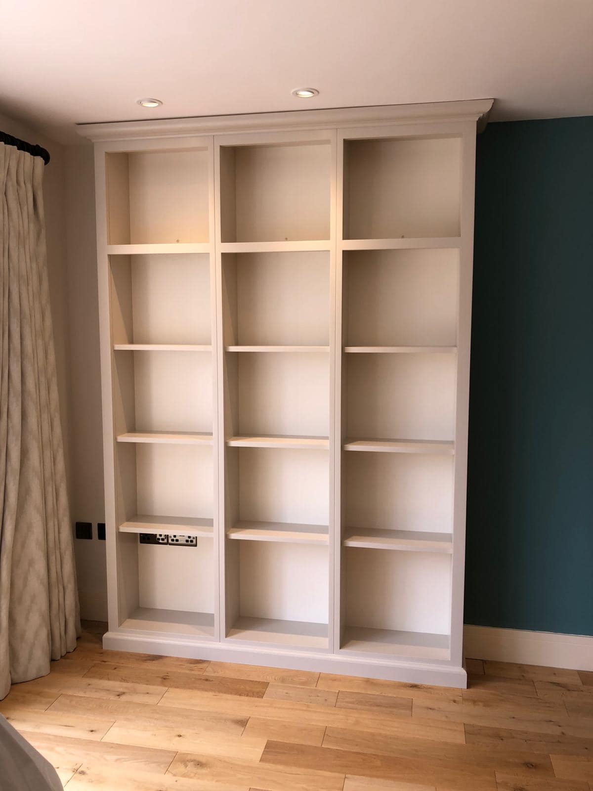 a tall light grey bookcase on a wooden floor