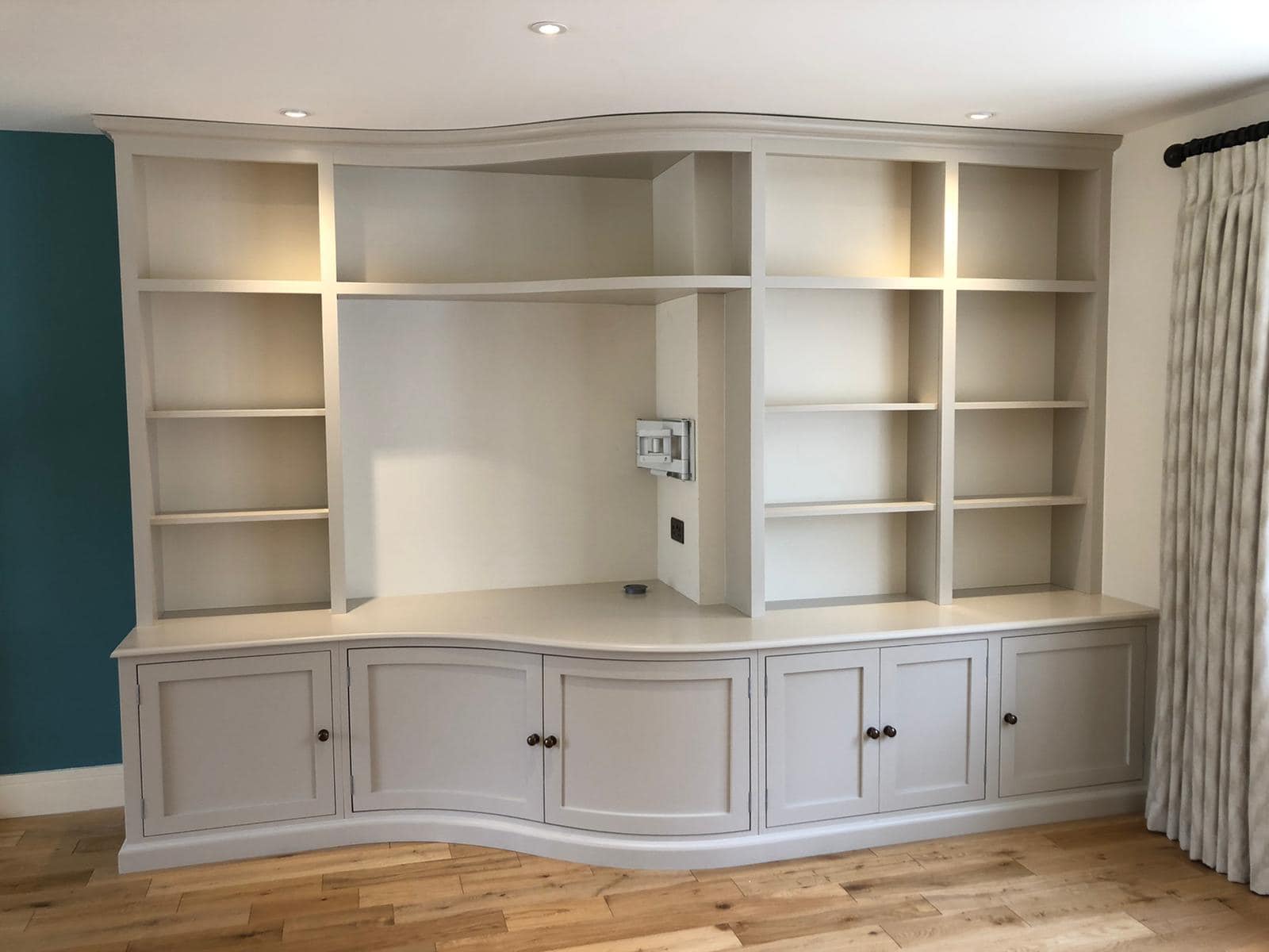 A curved book case and TV unit in a well lit room