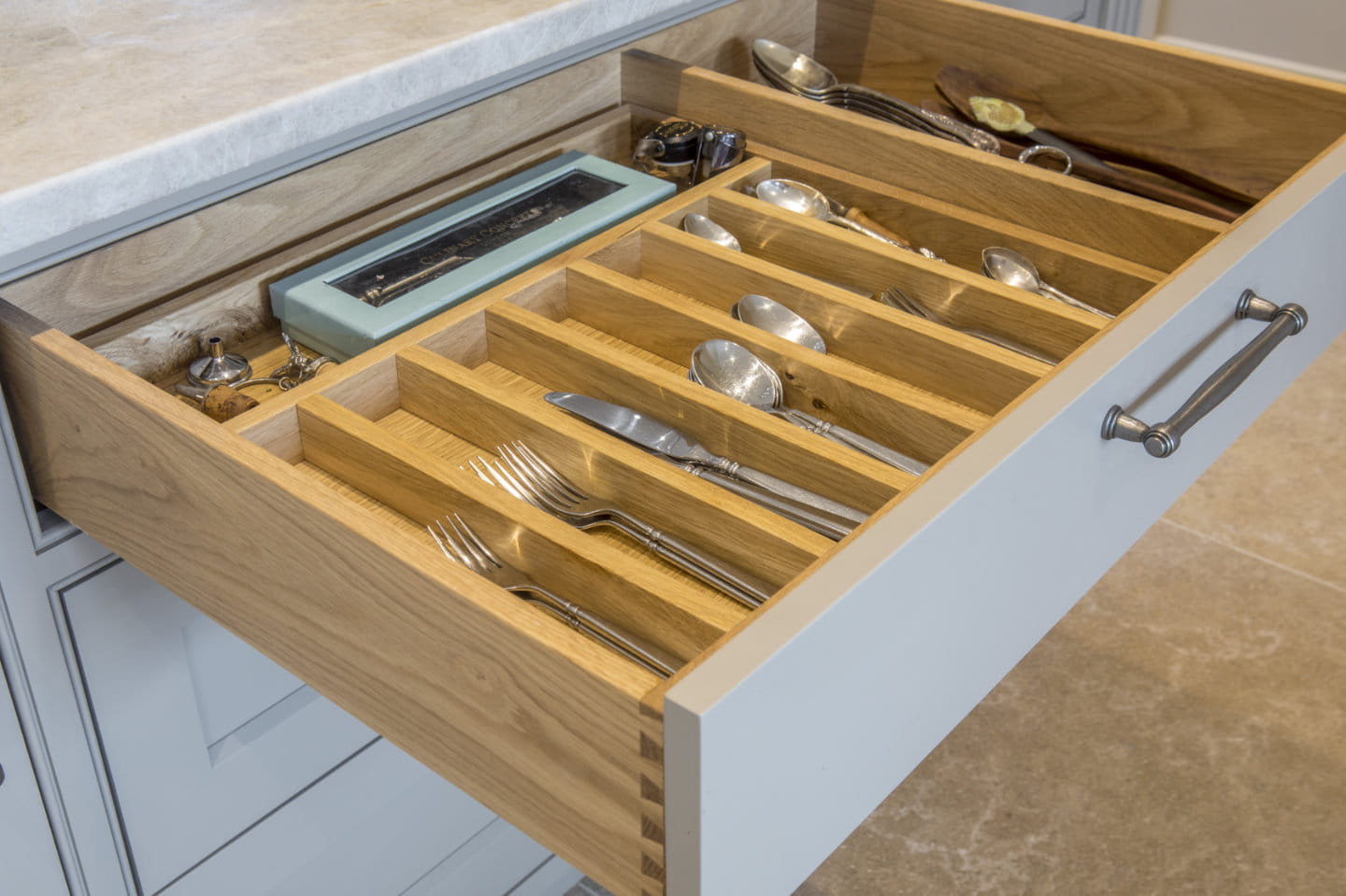 A kitchen drawer which has been opened to reveal the utensils inside.