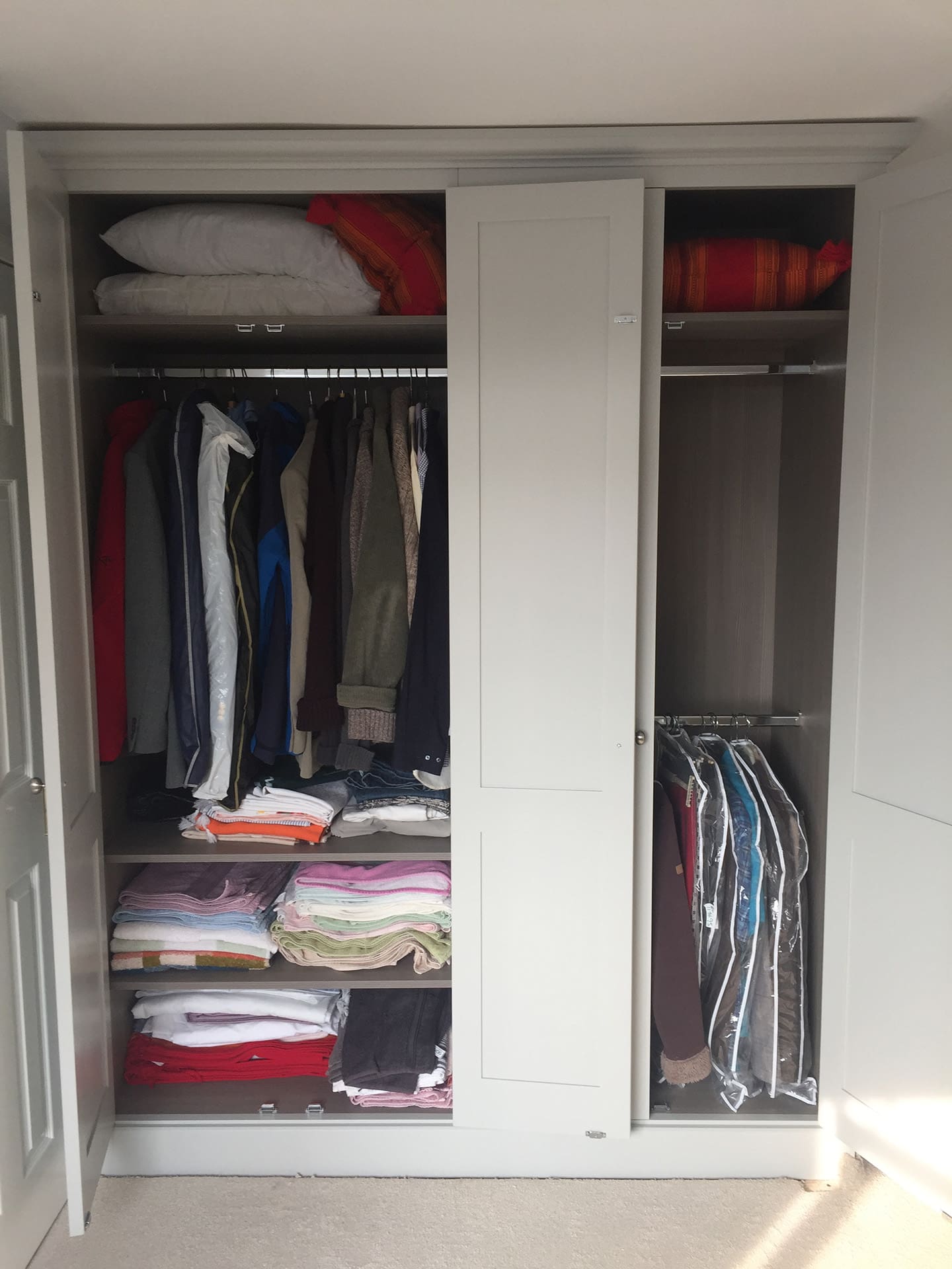 Wardrobes open to reveal the clothes hanging inside.