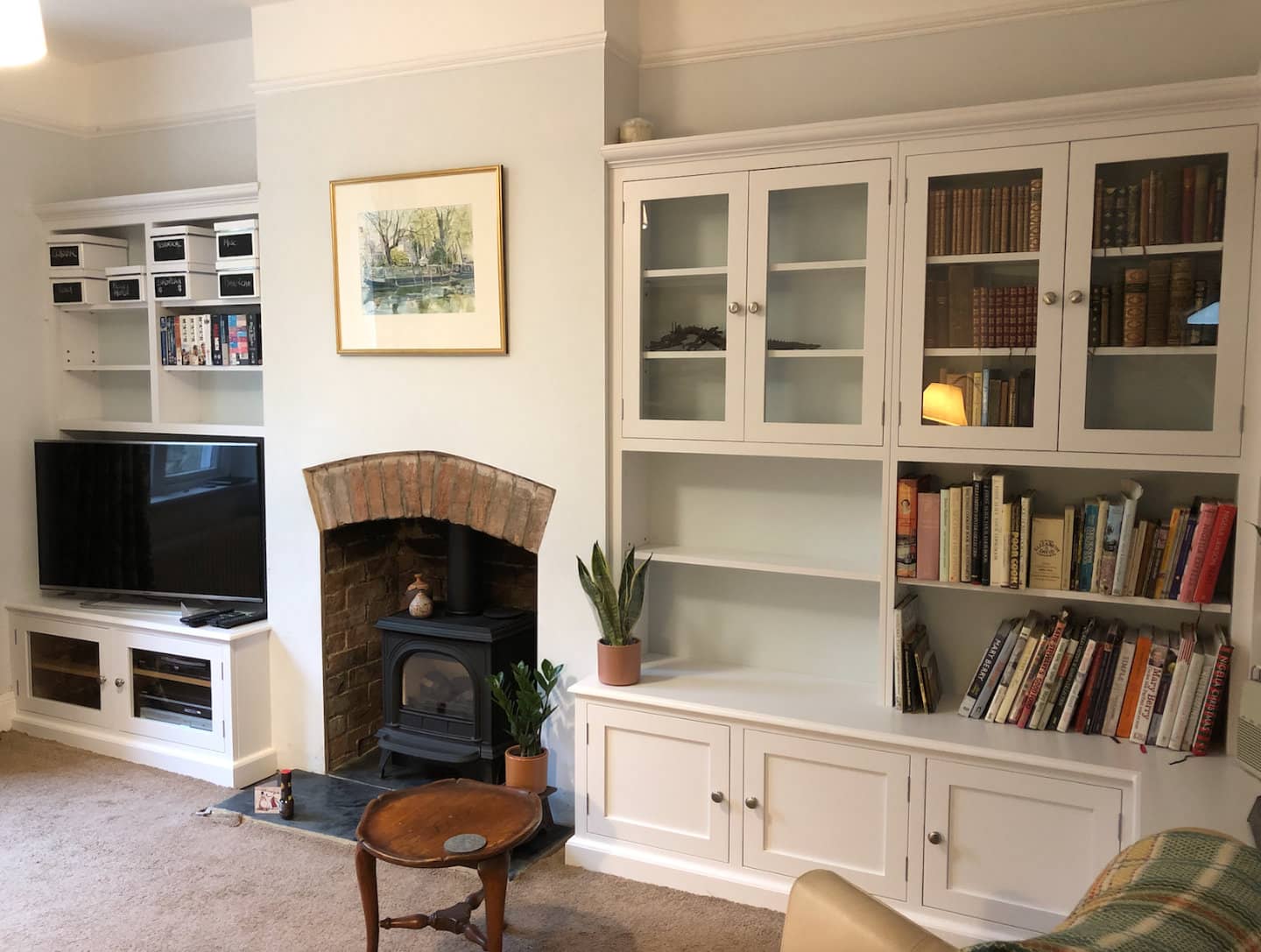 Two bespoke bookcases with an assortment of books and ornaments placed upon it.