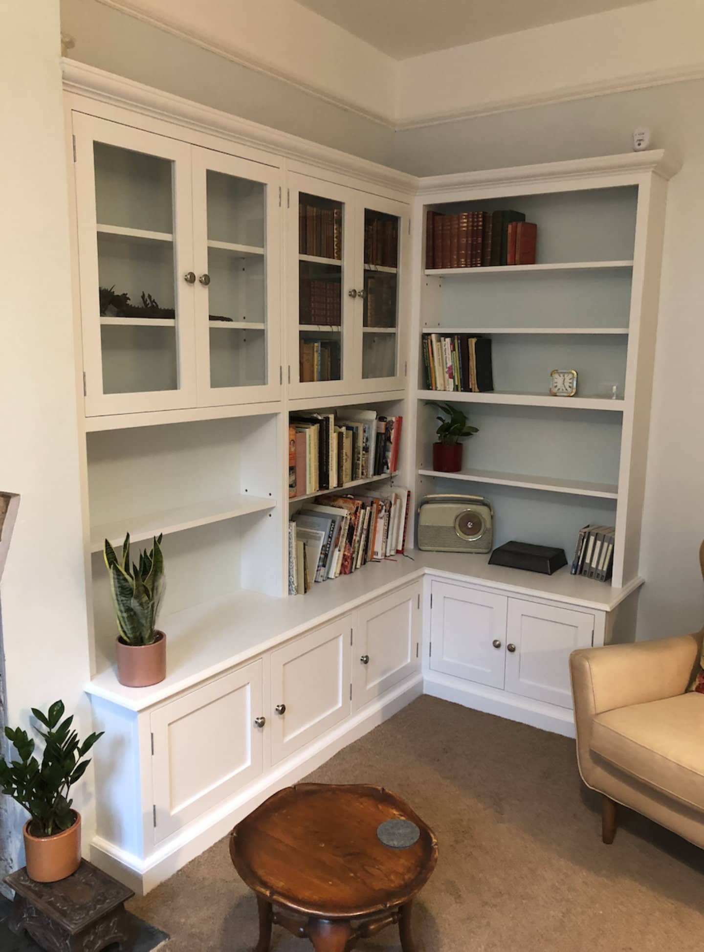 A bespoke corner bookcase with books and ornaments place upon it.