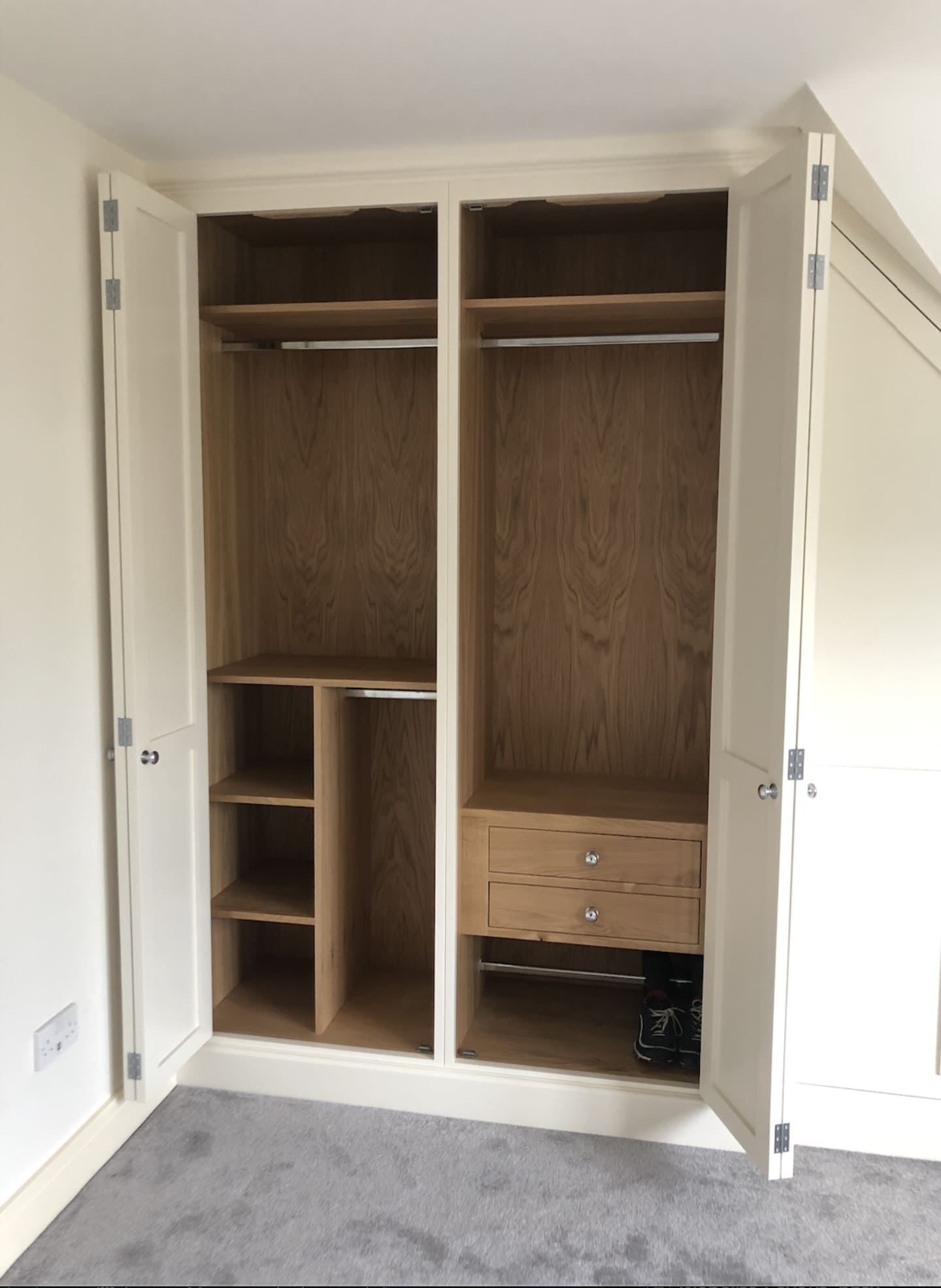 A bespoke fitted wardrobe with the doors open showing the custom interior.