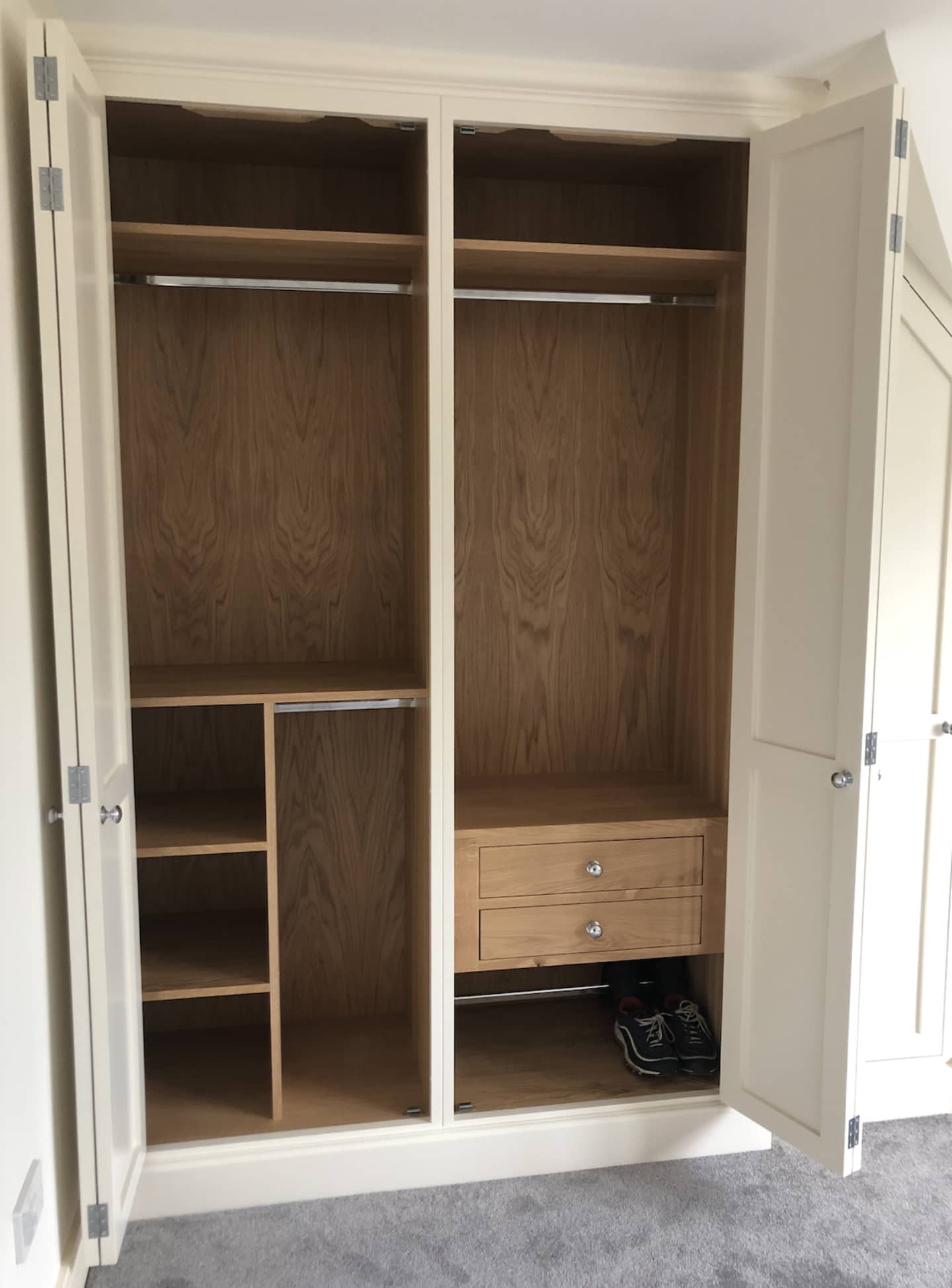 A bespoke fitted wardrobe with the doors open showing the custom interior.