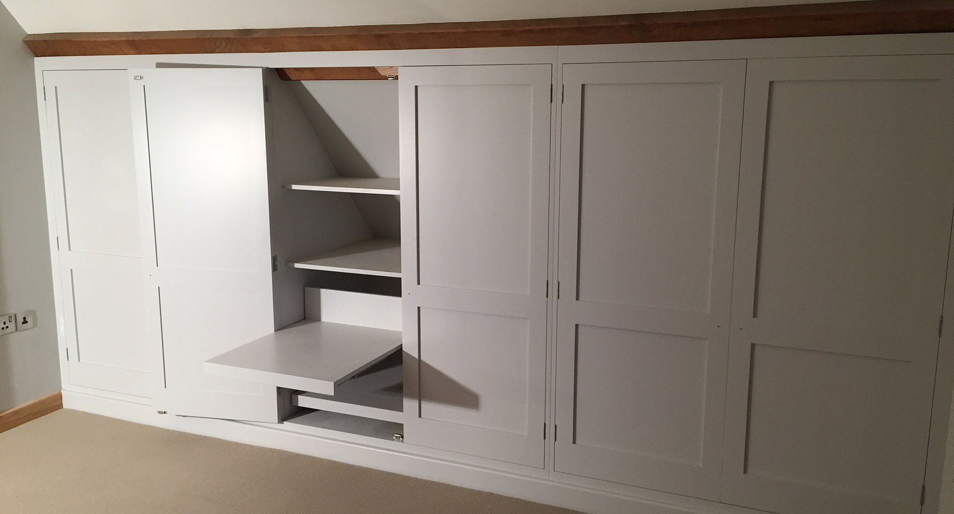 An integrated set of wardrobes with shelves which slide outwards.