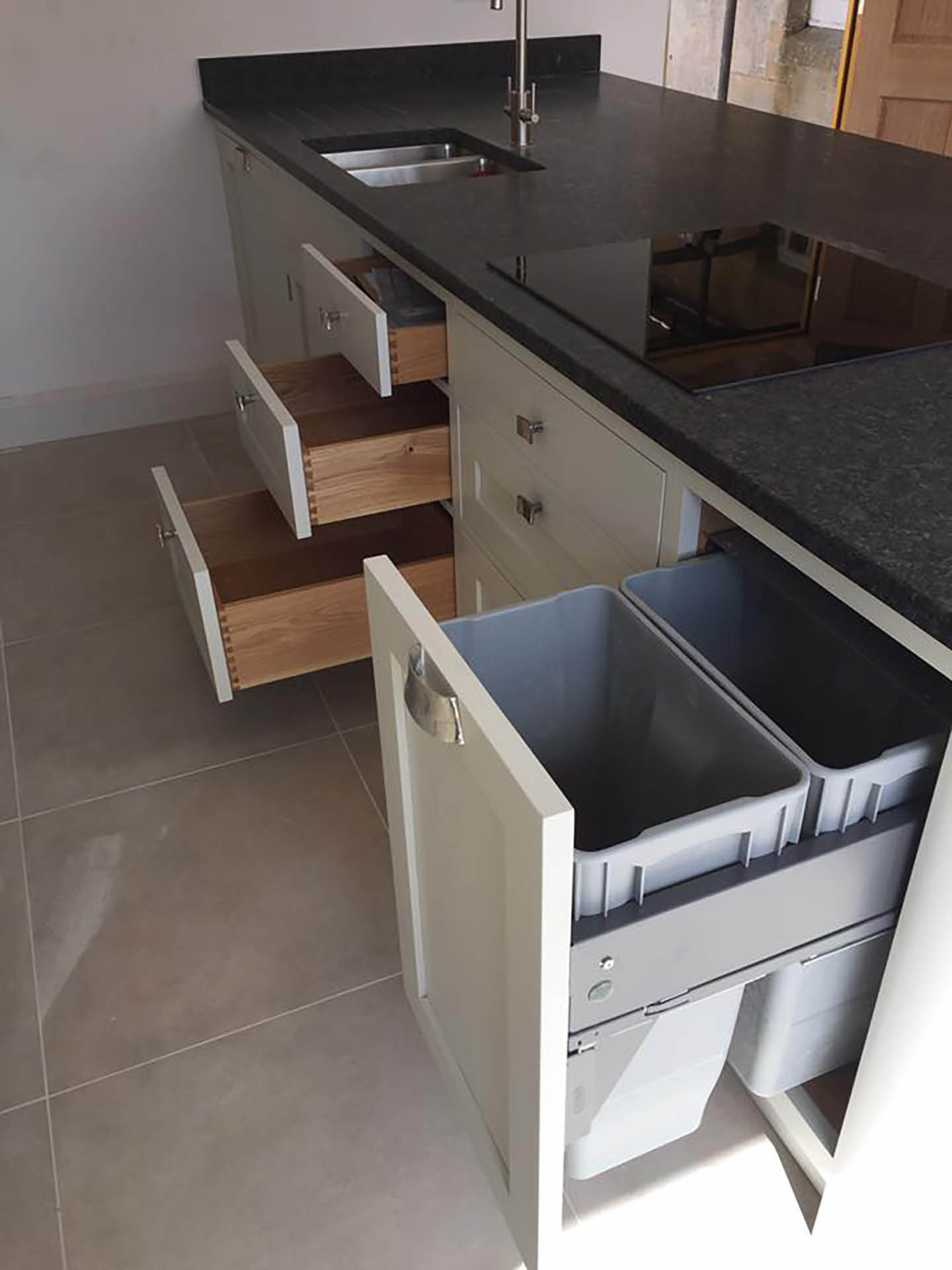 Kitchen cupboards showing some open drawers and a slide out bin.