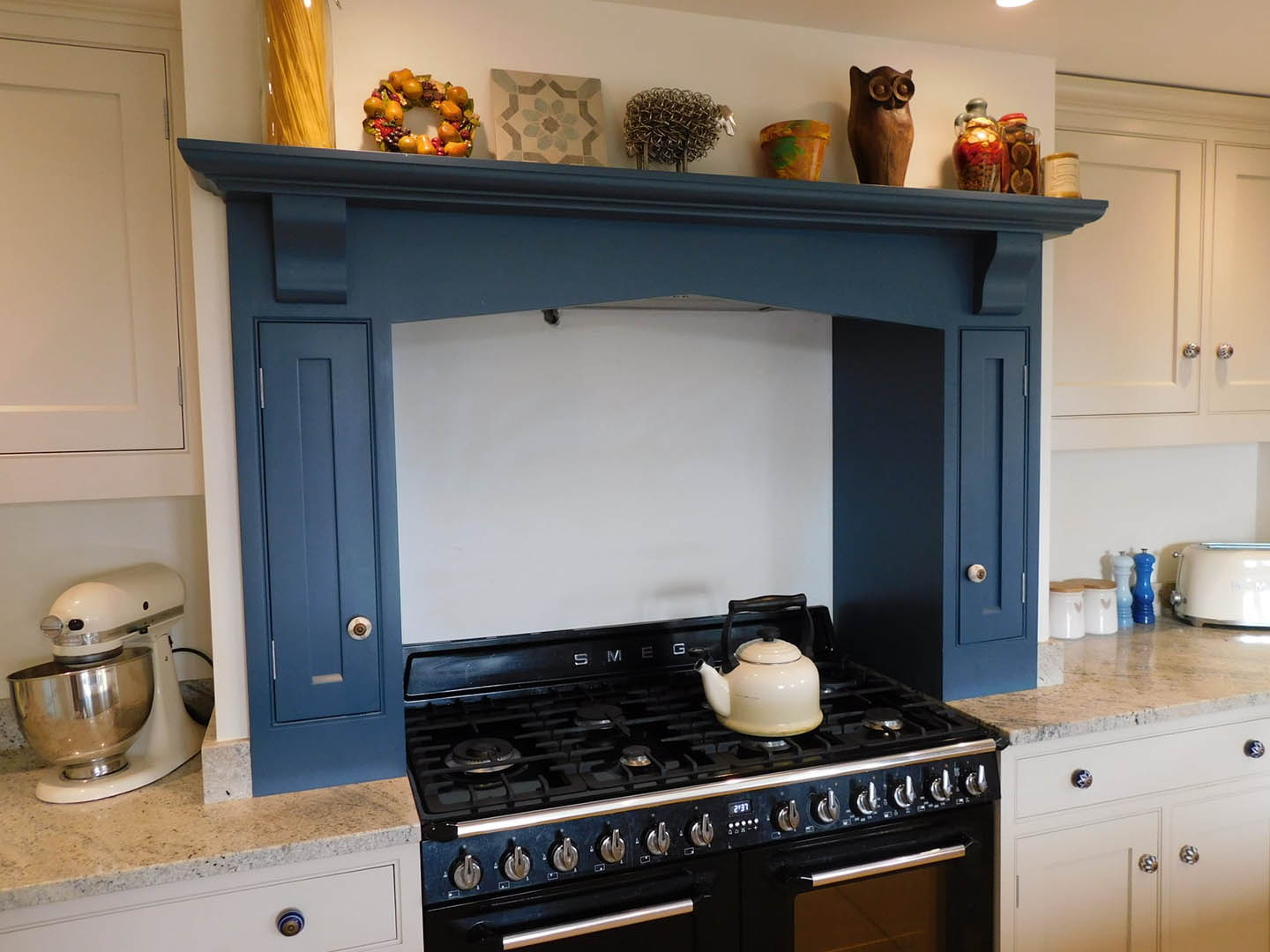 A kitchen cooker hood over a stove with a kettle on one of the hobs.